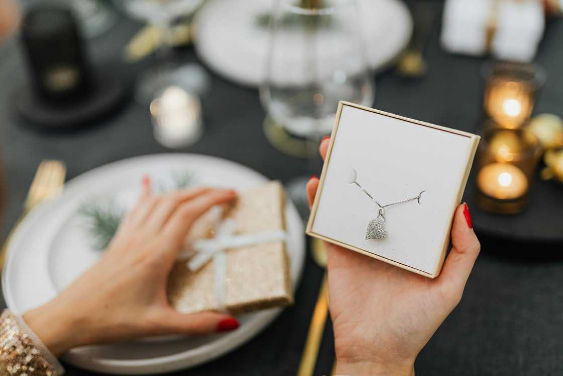 A lady holding a box with a love heart necklace