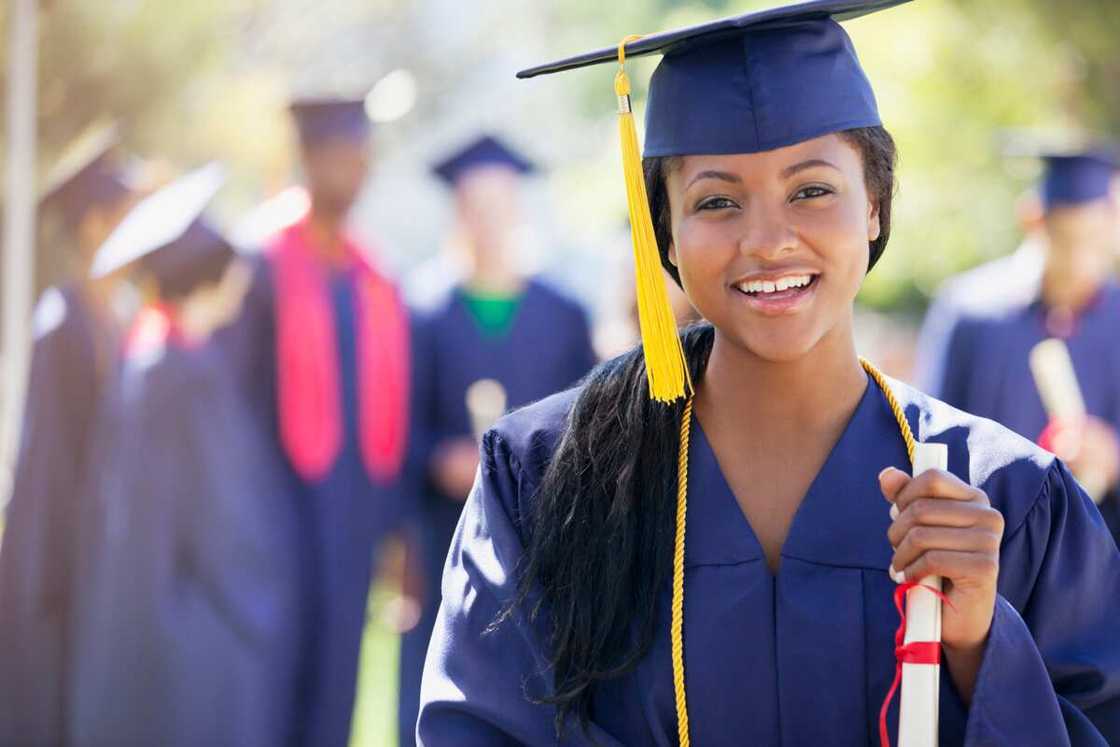 A lady dressed in a graduation gown and cap posing for a photo after the graduation ceremony