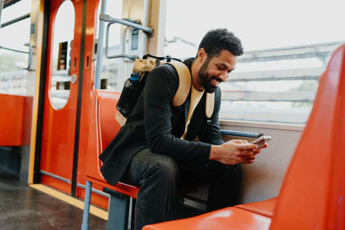 A smiling man scrolling on a smartphone