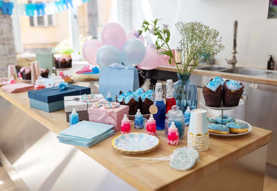 Baby shower party table with sweets, gifts, food and drinks.