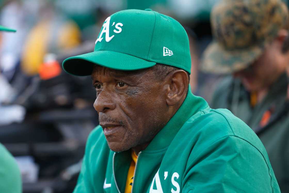 Rickey Henderson looks on in a green cap and jacket