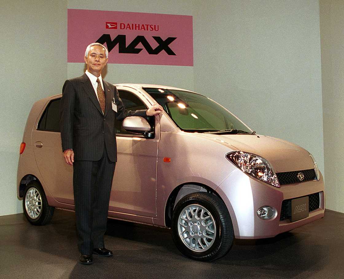 Japan's Daihatsu Motor President Takaya Yamada standing next to a Daihatsu MAX