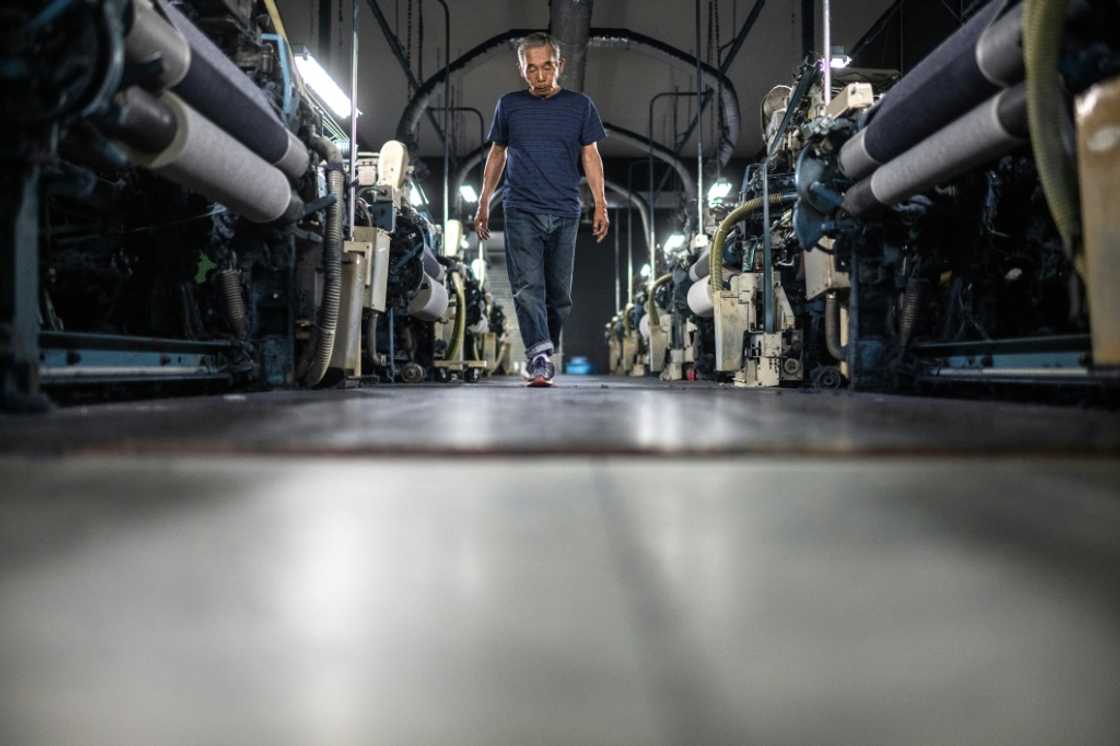 Weaving craftsman Shigeru Uchida walks between looms to detect unusual sounds that could signal a breakdown at the Momotaro Jeans factory