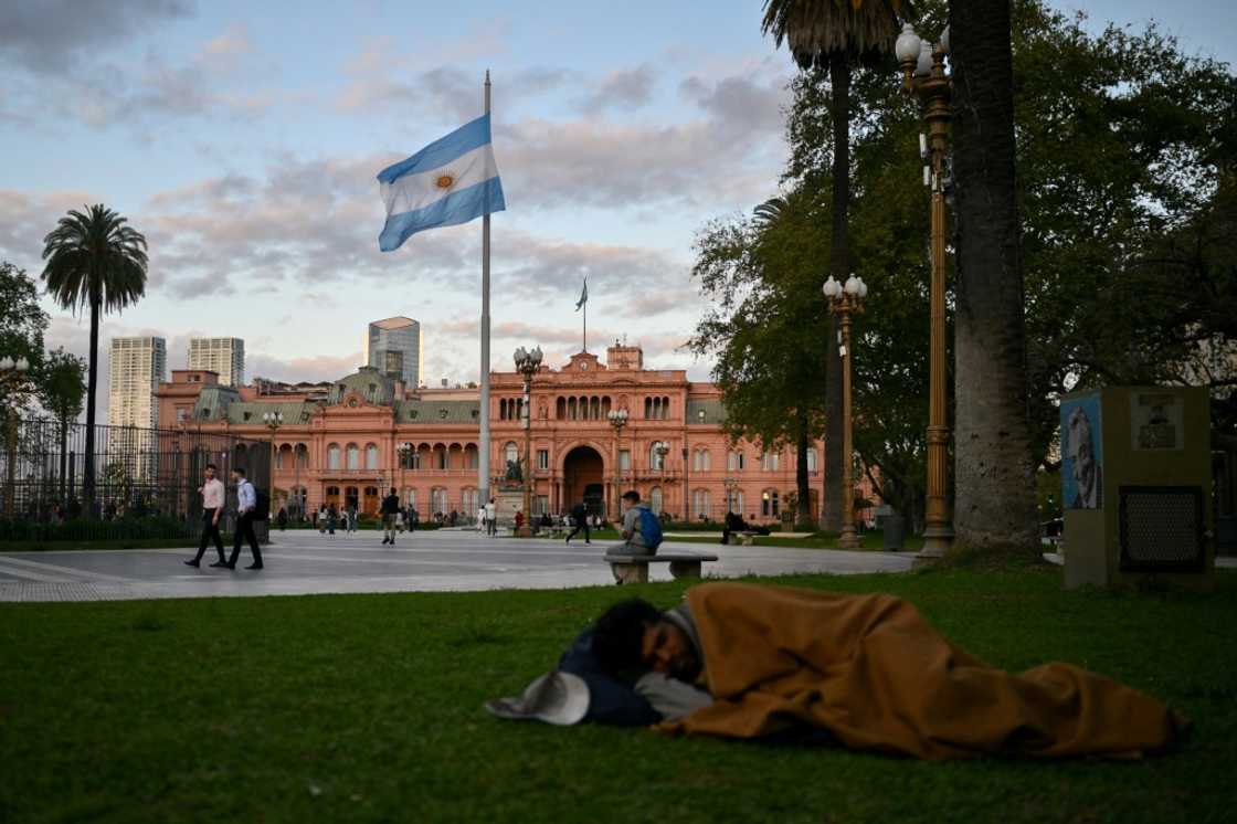 (FILES) A homeless man sleeps at Plaza de Mayo square in front of the Casa Rosada presidential palace in Buenos Aires on September 25, 2024