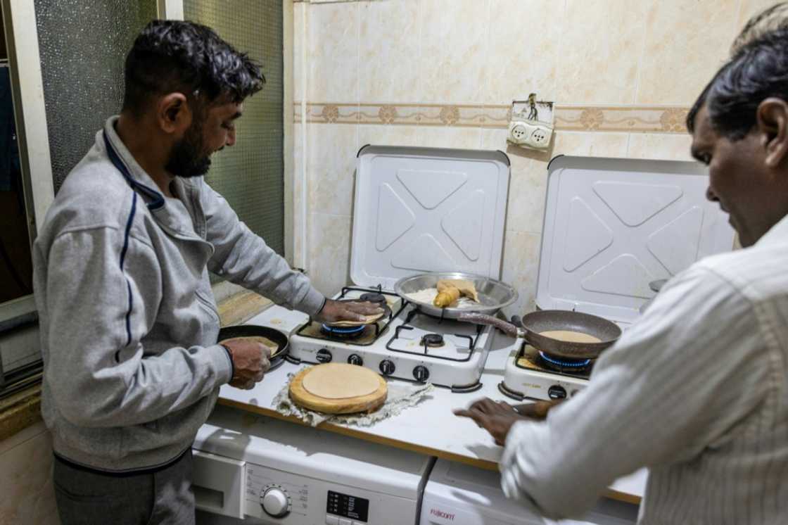 Thousands of kilometres from home, Indian construction workers prepare a meal at their flat in the Israeli coastal city of Tel Aviv