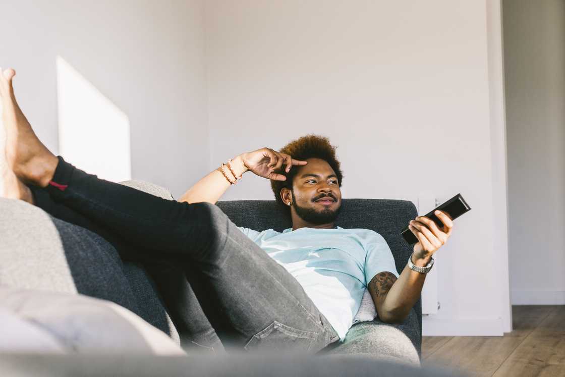 Young man lying on couch watching TV