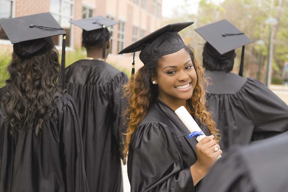 A lady excitedly holding her diploma after the college graduation ceremony