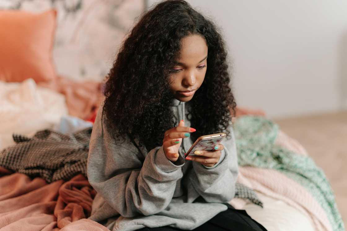 A girl-sitting-on-bed-using-cellphone