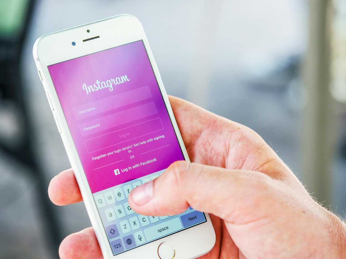 Person holding phone while logging in on Instagram application